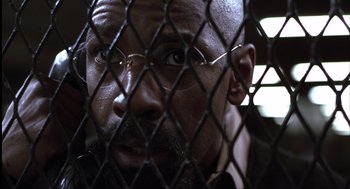 Movie still from “The Hurricane” (1999), directed by Norman Jewison – A person behind a chain link fence; Close Up shot, Over the shoulder angle