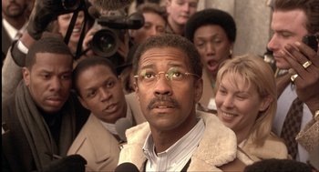 Movie still from “The Hurricane” (1999), directed by Norman Jewison – A group of people gathered around a man wearing glasses; Close Up shot, Low angle