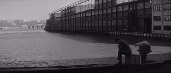 Movie still from “The Hustler” (1961), directed by Robert Rossen – A man sitting on a dock next to a body of water; Wide shot, High angle