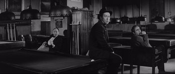 Movie still from “The Hustler” (1961), directed by Robert Rossen – A man sitting at a pool table in front of another man; Medium shot, Over the shoulder angle