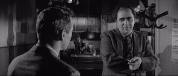 Movie still from “The Hustler” (1961), directed by Robert Rossen – Two men in suits are talking in a room; Medium shot, Over the shoulder angle