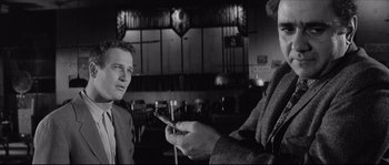 Movie still from “The Hustler” (1961), directed by Robert Rossen – A man and a woman are looking at a cell phone; Medium shot, Over the shoulder angle