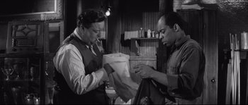 Movie still from “The Hustler” (1961), directed by Robert Rossen – Two men are looking at papers in a bar; Medium shot, Over the shoulder angle