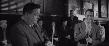 Movie still from “The Hustler” (1961), directed by Robert Rossen – A group of men sitting in a row holding candles; Medium shot, Over the shoulder angle