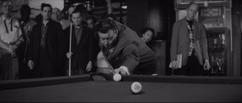 Movie still from “The Hustler” (1961), directed by Robert Rossen – A black and white photo of a man playing a game of billiards; Medium shot, High angle
