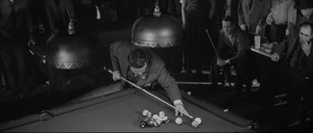 Movie still from “The Hustler” (1961), directed by Robert Rossen – A man in a suit playing a game of billiards; Medium shot, High angle