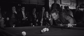 Movie still from “The Hustler” (1961), directed by Robert Rossen – A group of people sitting around a pool table; Medium shot, Over the shoulder angle