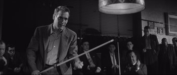 Movie still from “The Hustler” (1961), directed by Robert Rossen – A black and white photo of a man holding a stick; Medium shot, Over the shoulder angle