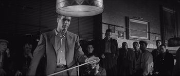 Movie still from “The Hustler” (1961), directed by Robert Rossen – A black and white photo of a man holding a cue; Medium shot, Low angle