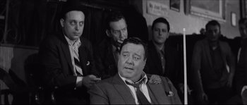 Movie still from “The Hustler” (1961), directed by Robert Rossen – A black - and - white photo of a group of men in suits; Medium shot, Over the shoulder angle