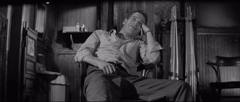 Movie still from “The Hustler” (1961), directed by Robert Rossen – A black and white photo of a man sitting in a rocking chair; Medium shot, High angle