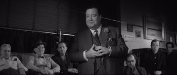 Movie still from “The Hustler” (1961), directed by Robert Rossen – A black and white photo of a man in a suit and tie; Medium shot, Over the shoulder angle