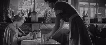 Movie still from “The Hustler” (1961), directed by Robert Rossen – A woman in an apron standing at a table with a cup; Medium shot, Low angle