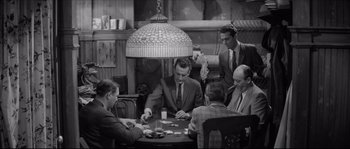 Movie still from “The Hustler” (1961), directed by Robert Rossen – A black and white photo of a group of men sitting at a table; Wide shot, High angle