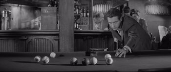 Movie still from “The Hustler” (1961), directed by Robert Rossen – A black and white photo of a man at a pool table; Medium shot, High angle