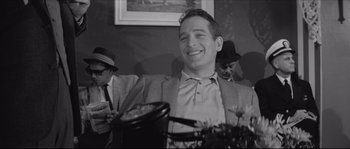 Movie still from “The Hustler” (1961), directed by Robert Rossen – A black and white photo of a man smiling; Close Up shot, Over the shoulder angle