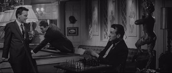 Movie still from “The Hustler” (1961), directed by Robert Rossen – A black and white photo of a man playing a game of chess; Medium shot, Over the shoulder angle