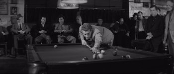 Movie still from “The Hustler” (1961), directed by Robert Rossen – A man playing pool while others watch from behind him; Medium shot, High angle