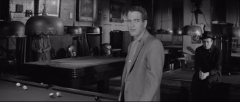 Movie still from “The Hustler” (1961), directed by Robert Rossen – A black and white photo of a man standing in a room; Medium shot, Over the shoulder angle
