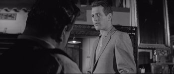 Movie still from “The Hustler” (1961), directed by Robert Rossen – A man in a suit talking to a woman in front of a mirror; Medium shot, Over the shoulder angle
