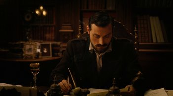 Movie still from “The Illusionist” (2006), directed by Neil Burger – A man sitting at a table writing on a piece of paper; Medium shot, High angle