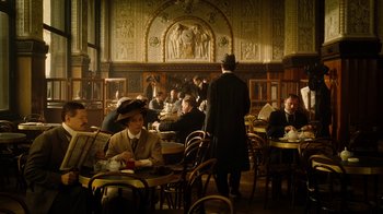 Movie still from “The Illusionist” (2006), directed by Neil Burger – A group of people sitting at tables in a room; Wide shot, High angle