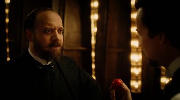 Movie still from “The Illusionist” (2006), directed by Neil Burger – A man with a goatee and a beard is holding an apple; Close Up shot, Over the shoulder angle