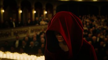 Movie still from “The Illusionist” (2006), directed by Neil Burger – A person with a red hood is standing in front of a crowd of people; Medium shot, Low angle