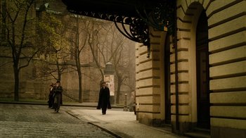 Movie still from “The Illusionist” (2006), directed by Neil Burger – A person walking down a street near a building; Extreme Wide shot, High angle