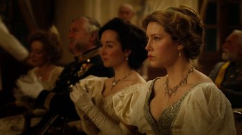 Movie still from “The Illusionist” (2006), directed by Neil Burger – A group of people sitting next to each other in formal wear; Medium shot, Low angle
