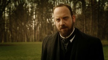 Movie still from “The Illusionist” (2006), directed by Neil Burger – A man with a goatee standing in front of trees; Close Up shot, Low angle