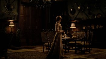 Movie still from “The Illusionist” (2006), directed by Neil Burger – A woman standing in front of a dining room table; Wide shot, Over the shoulder angle