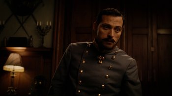 Movie still from “The Illusionist” (2006), directed by Neil Burger – A man in a military uniform standing next to a wall; Close Up shot, Over the shoulder angle