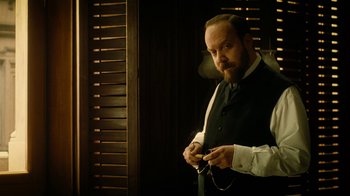 Movie still from “The Illusionist” (2006), directed by Neil Burger – A man in a vest and tie looking at a cell phone; Close Up shot, Over the shoulder angle
