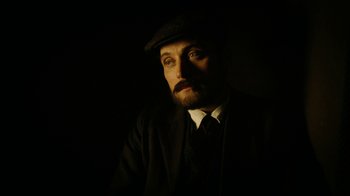 Movie still from “The Illusionist” (2006), directed by Neil Burger – A man with a beard wearing a suit and a hat; Close Up shot, Low angle