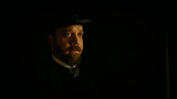Movie still from “The Illusionist” (2006), directed by Neil Burger – A man with a beard wearing a hat and a suit; Close Up shot, Low angle