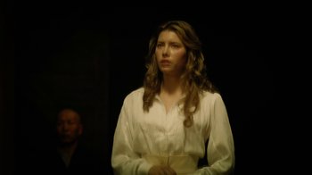 Movie still from “The Illusionist” (2006), directed by Neil Burger – A woman in a white shirt is standing in a dark room; Medium shot, Low angle