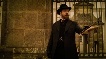 Movie still from “The Illusionist” (2006), directed by Neil Burger – A man in a black hat and a black coat; Medium shot, Low angle