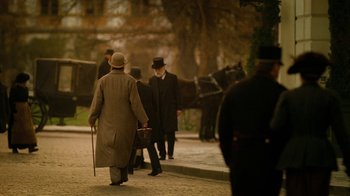 Movie still from “The Illusionist” (2006), directed by Neil Burger – A group of men walking down a street with a horse drawn carriage; Wide shot, Over the shoulder angle