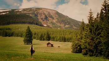 Movie still from “The Illusionist” (2006), directed by Neil Burger – A person walking in a field with a mountain in the background; Extreme Wide shot, High angle