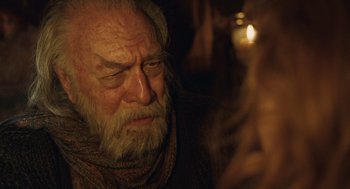 Movie still from “The Imaginarium of Doctor Parnassus” (2009), directed by Terry Gilliam – An old man with a beard is looking at a candle; Close Up shot, Over the shoulder angle