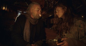 Movie still from “The Imaginarium of Doctor Parnassus” (2009), directed by Terry Gilliam – An older man and a younger woman sitting at a table; Medium shot, Low angle