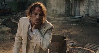 Movie still from “The Imaginarium of Doctor Parnassus” (2009), directed by Terry Gilliam – A man in a white suit with a red bandage on his forehead; Medium shot, Low angle