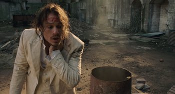 Movie still from “The Imaginarium of Doctor Parnassus” (2009), directed by Terry Gilliam – A man with a bandage on his head standing next to a barrel; Medium shot, High angle