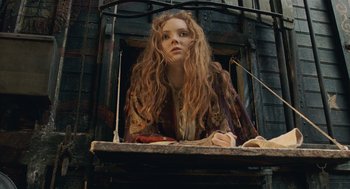 Movie still from “The Imaginarium of Doctor Parnassus” (2009), directed by Terry Gilliam – A woman with long red hair sitting on a window ledge; Medium shot, Low angle