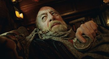 Movie still from “The Imaginarium of Doctor Parnassus” (2009), directed by Terry Gilliam – An old man with a beard and a coin in his mouth; Close Up shot, Low angle