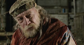 Movie still from “The Imaginarium of Doctor Parnassus” (2009), directed by Terry Gilliam – An old man with long white beard wearing a hat; Close Up shot, Over the shoulder angle