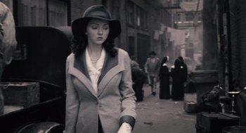 Movie still from “The Imaginarium of Doctor Parnassus” (2009), directed by Terry Gilliam – A black and white photo of a woman wearing a hat; Medium shot, Over the shoulder angle