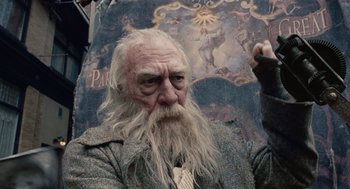 Movie still from “The Imaginarium of Doctor Parnassus” (2009), directed by Terry Gilliam – An old man with long white beard holding an umbrella; Medium shot, Low angle