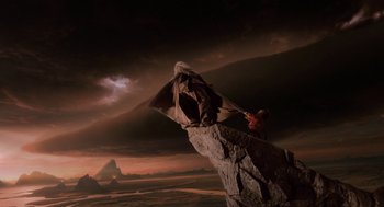 Movie still from “The Imaginarium of Doctor Parnassus” (2009), directed by Terry Gilliam – A man standing on top of a large rock in the middle of the night; Wide shot, Low angle
